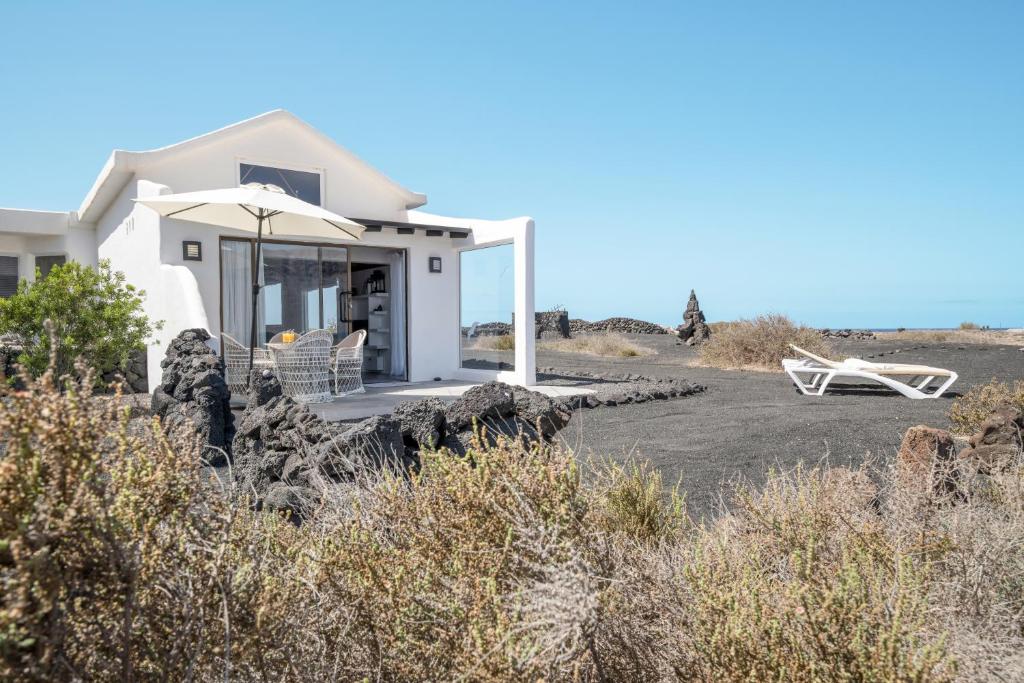 a house on the beach with an umbrella and chairs at El Loft in Famara