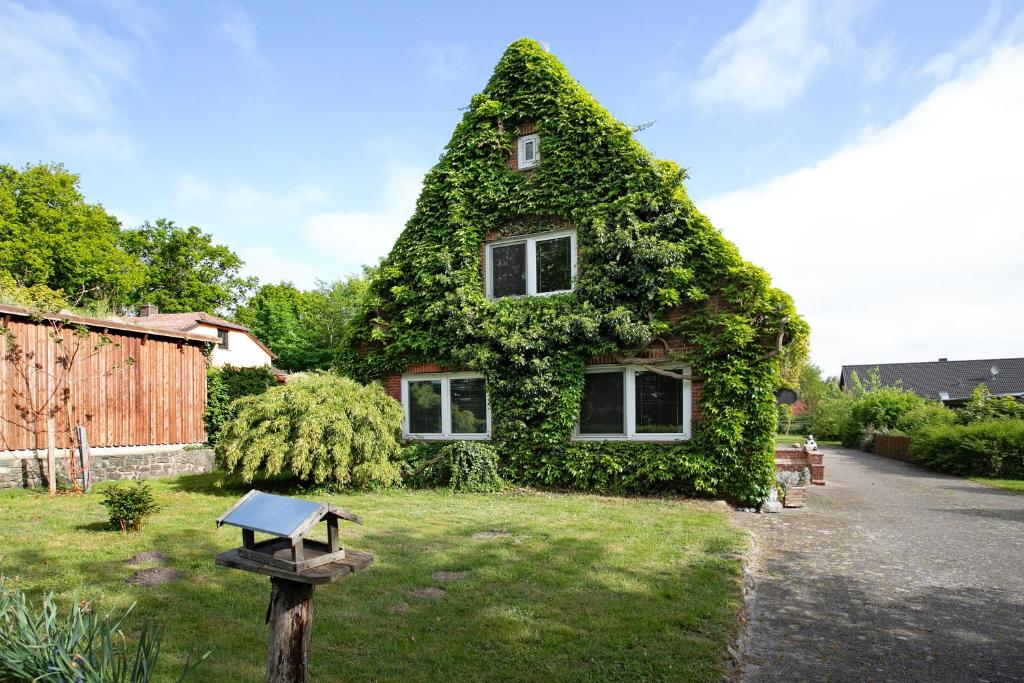 a house covered in ivy with a sign in front of it at Haus Gerda in Stadum