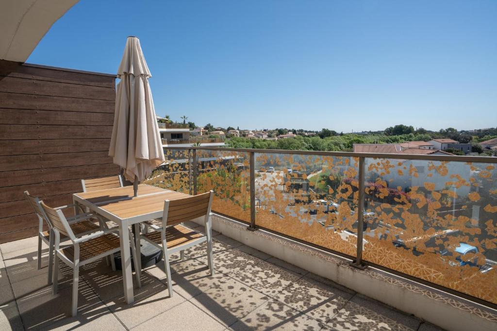 a table and chairs on a balcony with an umbrella at Appartement T2 Muses in Le Crès