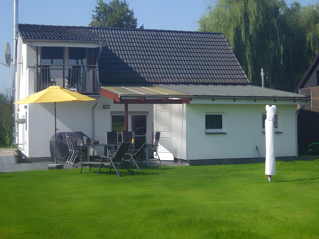 a white house with a table and chairs in a yard at Ferienhaus Kudensee in Kudensee