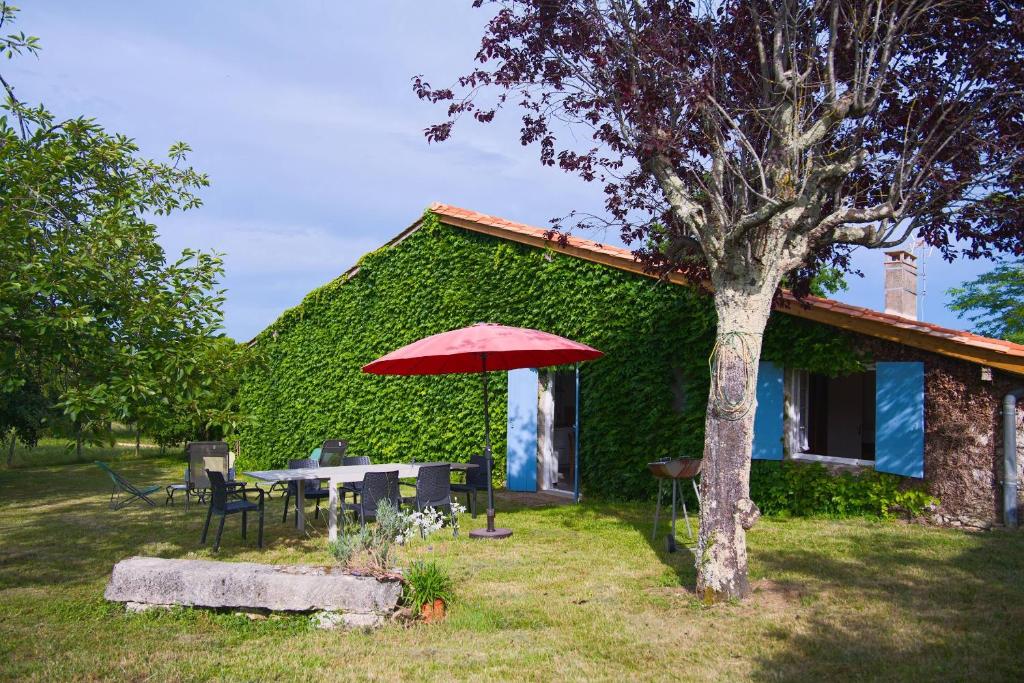 a house with a table and a red umbrella at Le Gite Du Vigneron Périgord in Razac-de-Saussignac