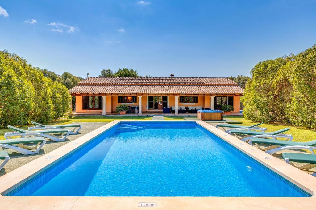 a swimming pool in front of a house with chairs at Finca Sa Pova in Alcudia
