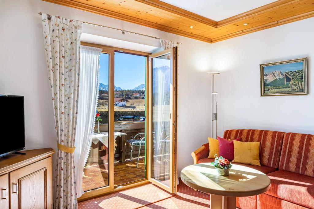 a living room with a couch and a table and a balcony at Alpenblick Tilly - Fewo Soiernsee 4 in Krün