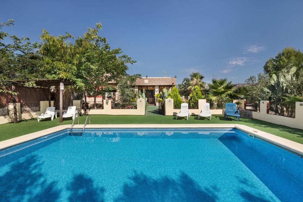a swimming pool with chairs and a yard at Capricho in Cieza