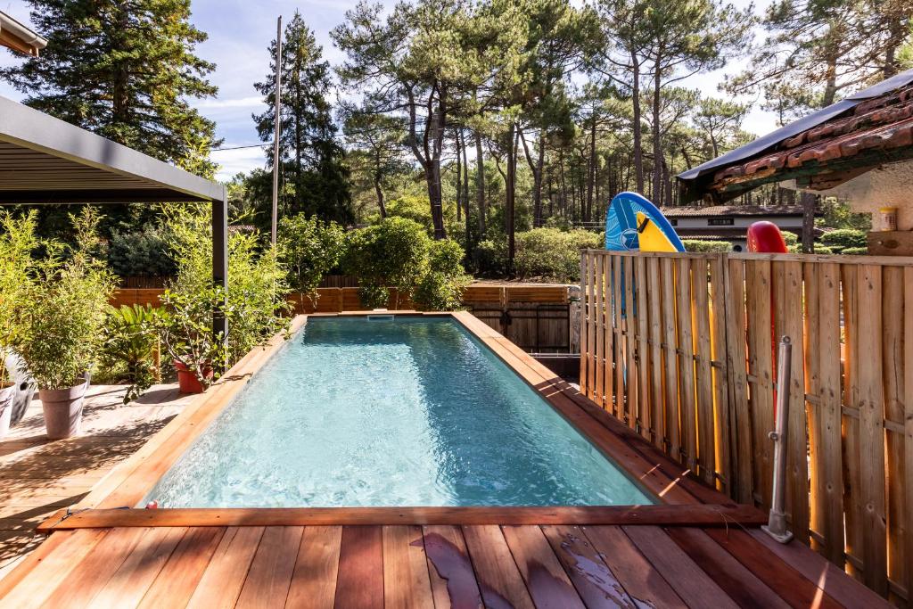 a swimming pool on a deck with a wooden fence at Les Ptis Chiffons in Lacanau