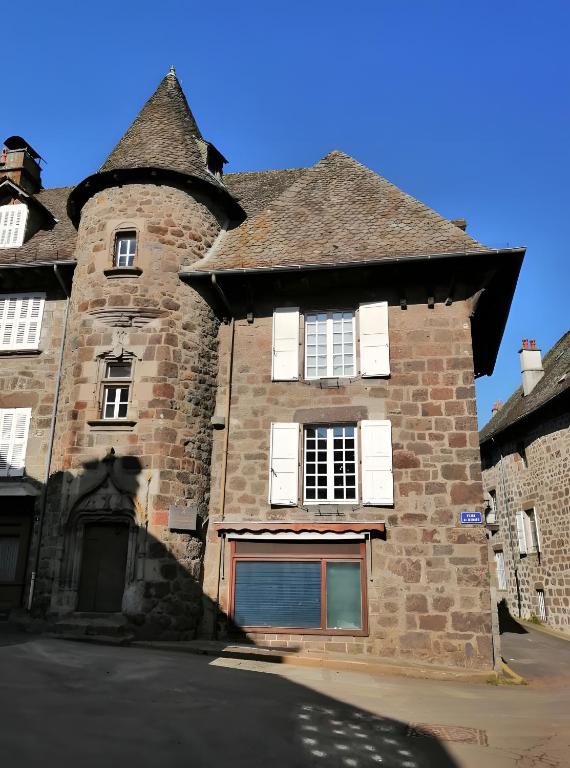 an old brick building with white shuttered windows at Maison des Princes de Monaco in Vic-sur-Cère
