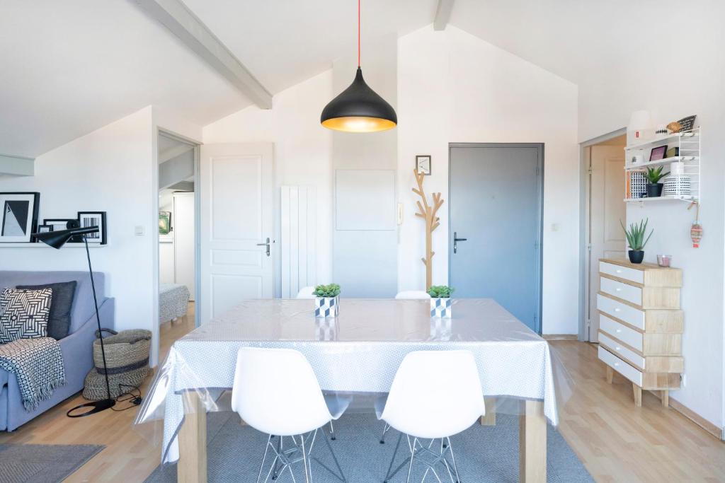 a dining room with a white table and white chairs at Charmant T2 centre Capbreton in Capbreton