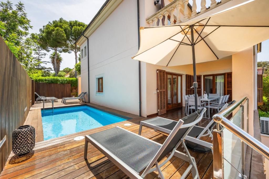 a patio with a pool and chairs and an umbrella at Tomymar in Cala Ratjada