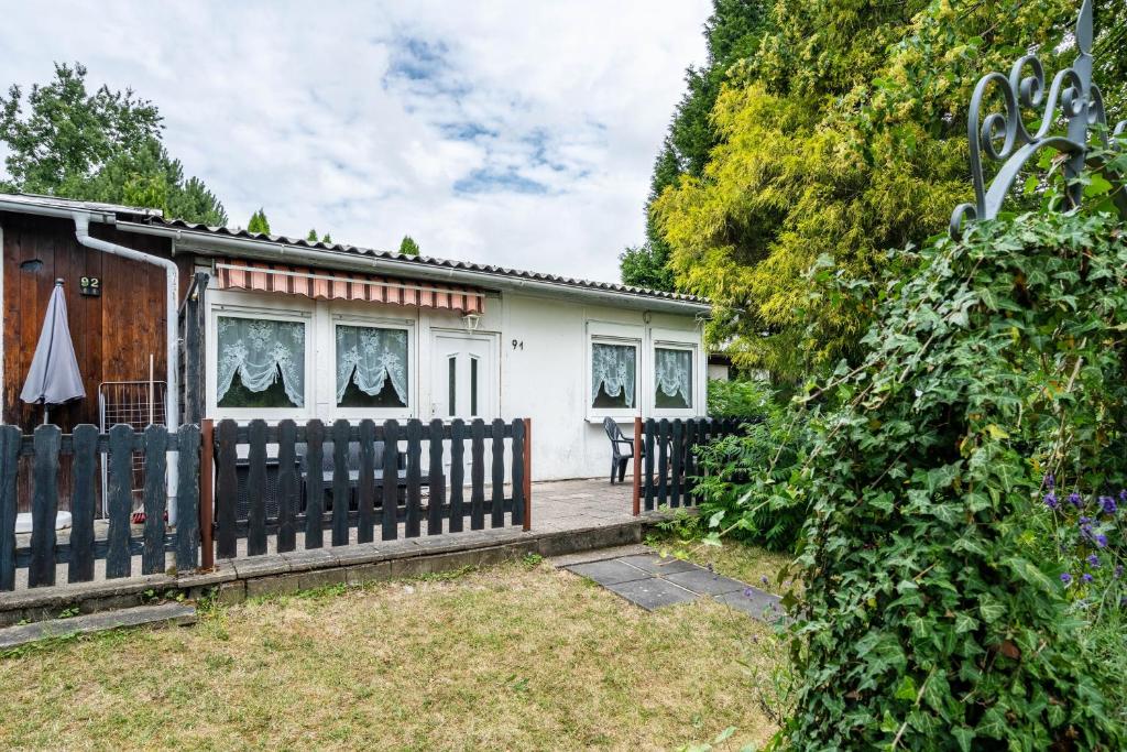 a small white house with a wooden fence at Bungalow 91 in Zeulenroda