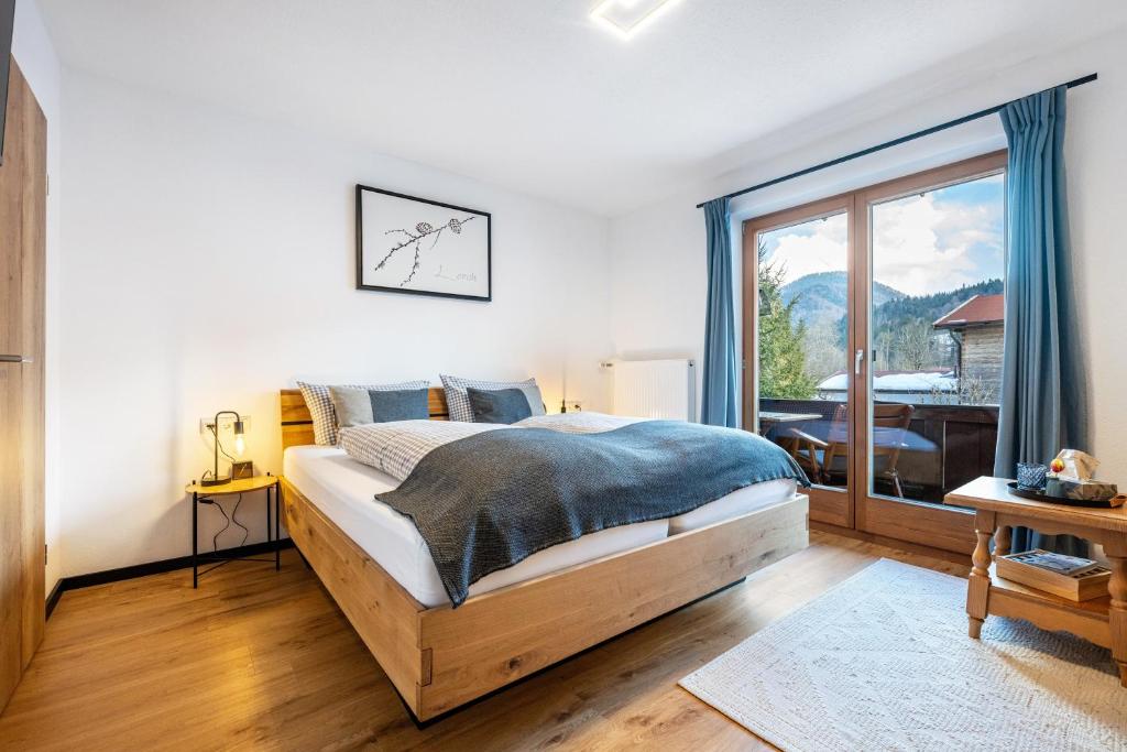 a bedroom with a bed and a large window at Fewo Am Steinbach - Lofer in Reit im Winkl