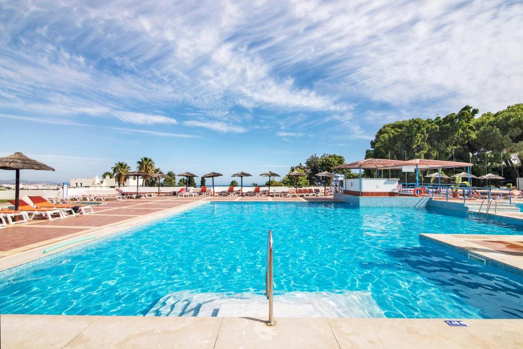 a large swimming pool with chairs and umbrellas at White Studio and Terrace in Albufeira