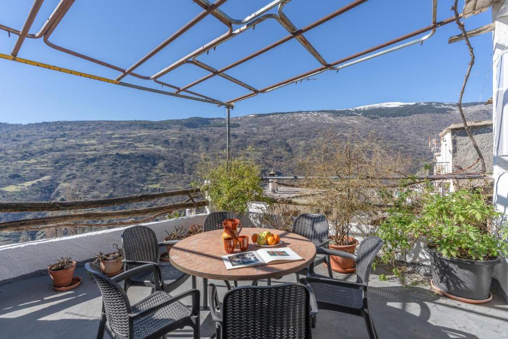a table and chairs on a balcony with a view at Casa El Portón, Bubión in Bubión