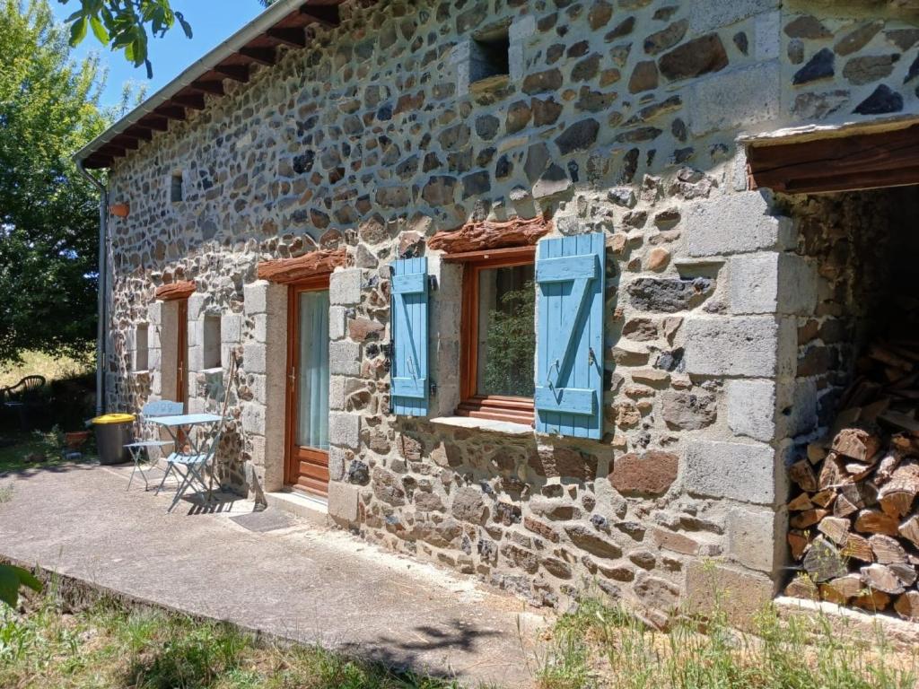 a stone house with blue windows and a table at La Garnasette in Beaulieu