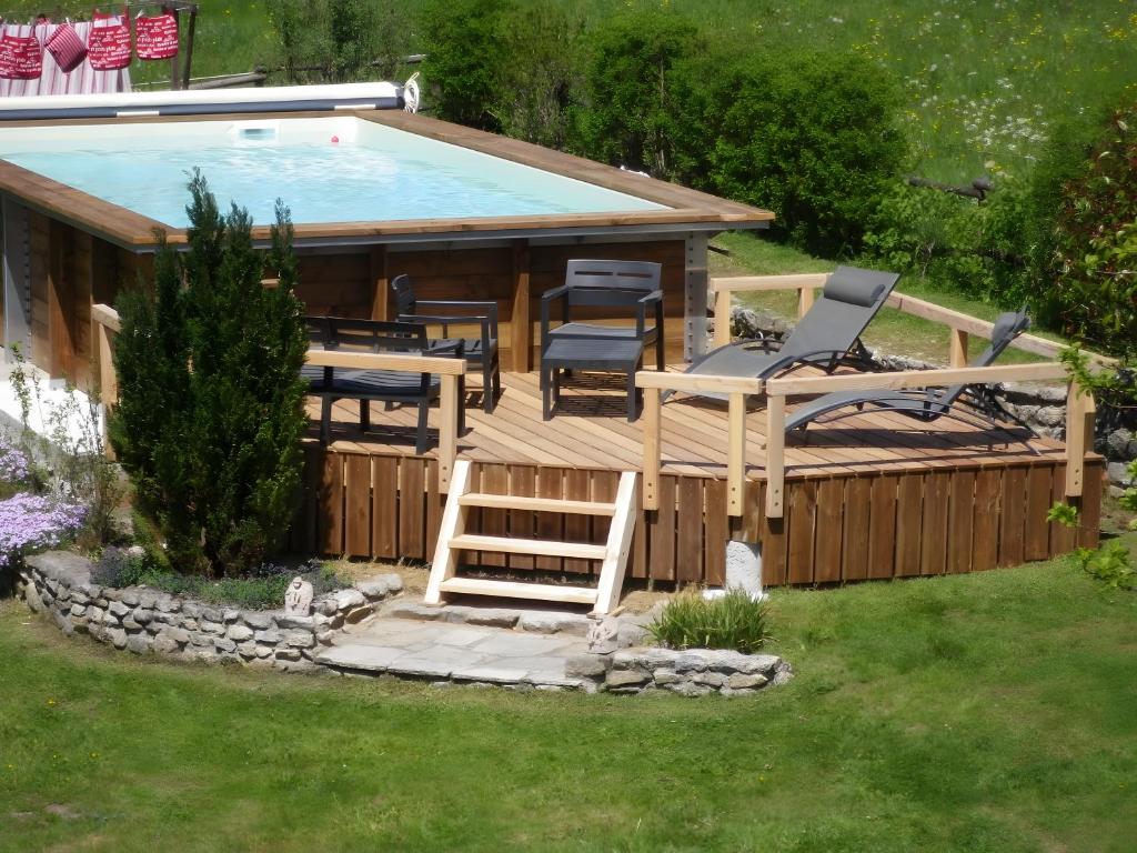 a deck with a pool and chairs and a house at Gîte Champêtre, Tout Confort in Saint-Éloy-la-Glacière