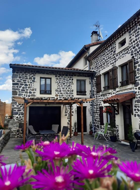 a stone house with purple flowers in front of it at Chambre et Table d’Hôtes du Terroir in Borne