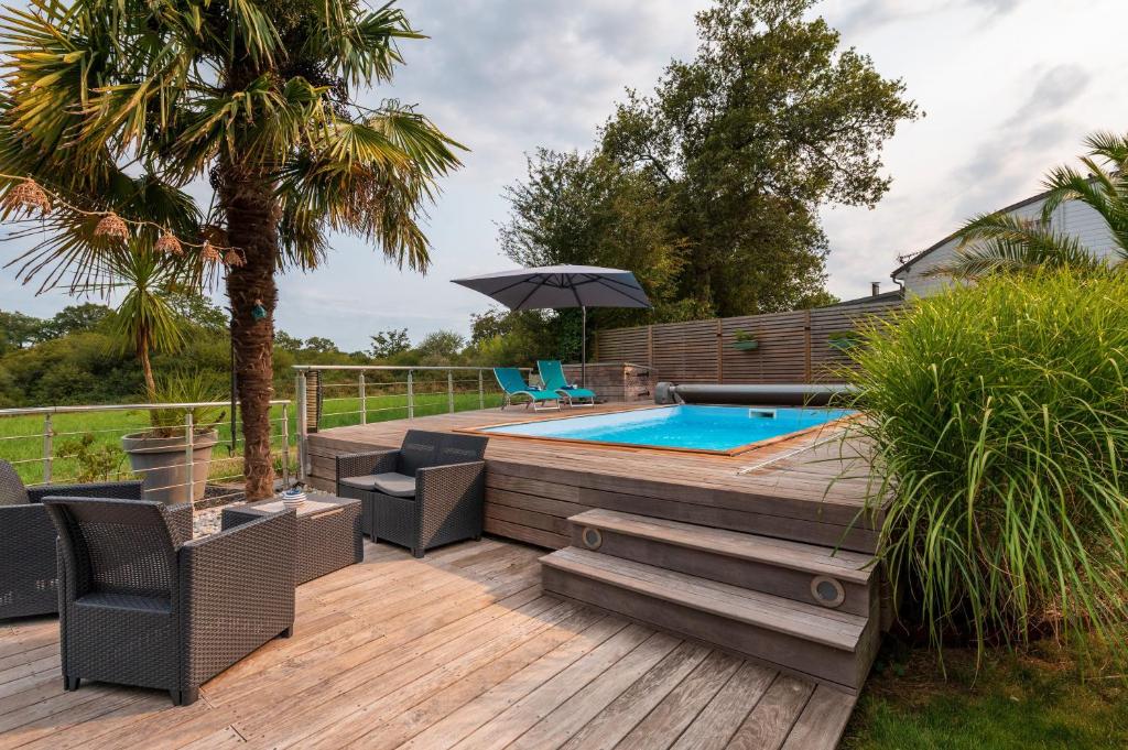 a deck with a pool and chairs and an umbrella at Côté Vannes in Ploeren