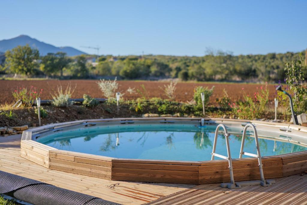 a large pool with a wooden deck around it at Gîte Des Louveteaux in Banne