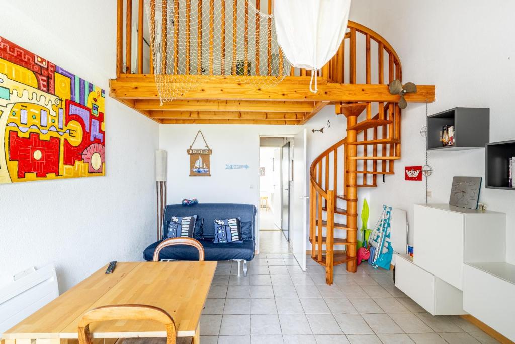a living room with a wooden staircase and a blue chair at La Cabine du Marin - 73 in Pornic