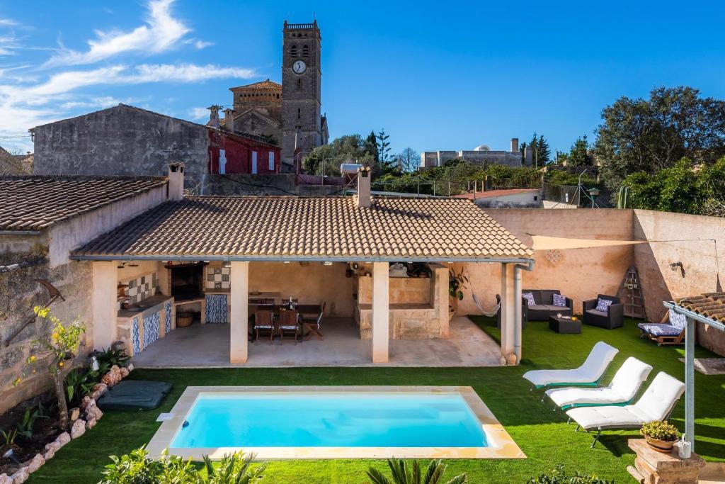 a villa with a swimming pool and a clock tower at Cas Padri Teco in Ariany