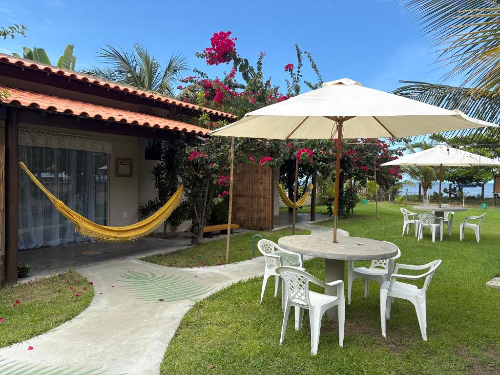 a patio with a table and chairs and an umbrella at Rancho Capilé Suítes à Beira Mar in Japaratinga
