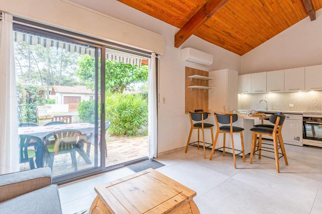 a kitchen and living room with a table and chairs at La maison des Prairies - Biscarosse in Biscarrosse