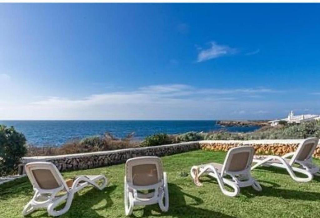 a group of chairs sitting on the grass near the ocean at Villa Bini Sek in Binibeca