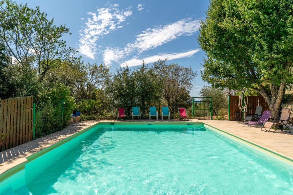 a swimming pool with blue chairs in a yard at Les Conils in Saint-Pierre-de-Vassols