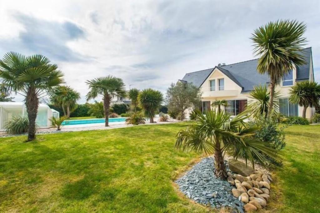a house with palm trees in the yard at Villa - Piscine, jacuzzi, sauna in Plouharnel