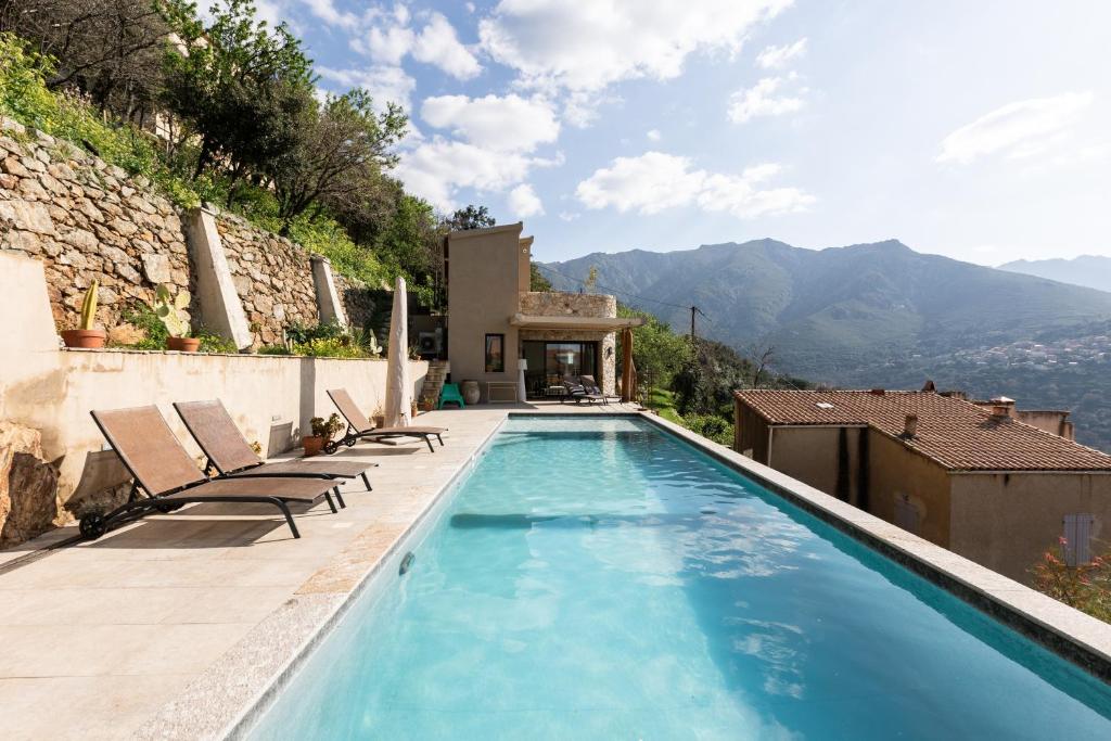 a swimming pool with chairs and a house at A Chiusella in Belgodère