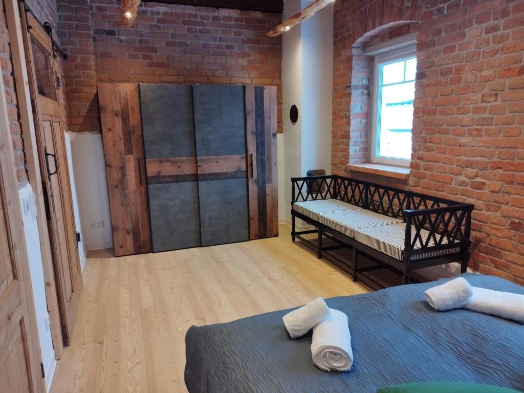 a room with a bed and a bench and a brick wall at Kleine Auszeit 2 in Forst