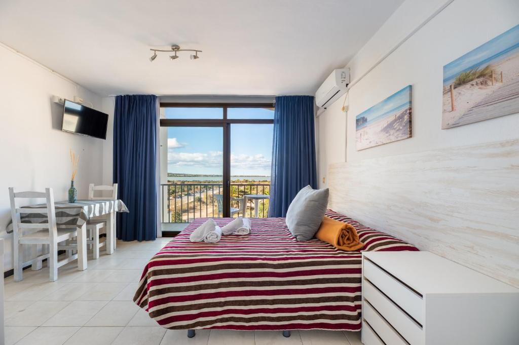 a bedroom with a large bed and a balcony at Estudio Mirada 309 in Es Pujols