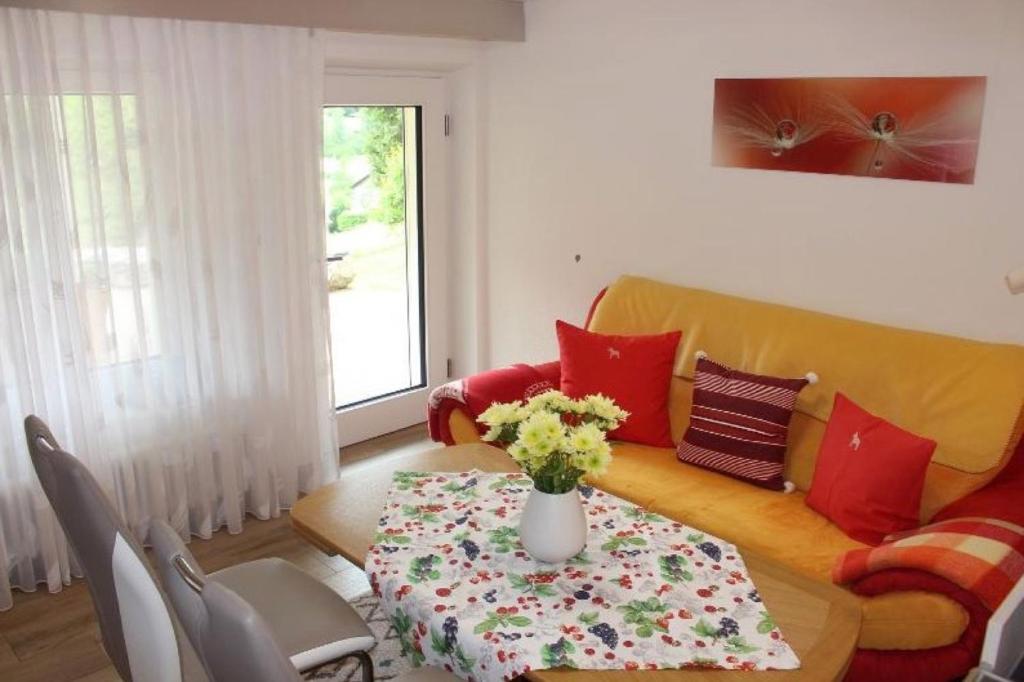 a living room with a couch and a table with flowers at Ferienwohnung Landidyll in Enzklösterle