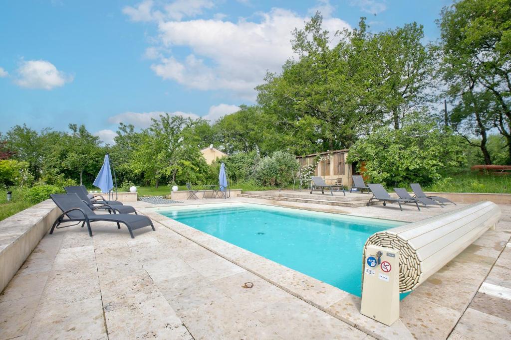 a swimming pool with two chairs and a bench next to it at Gite Deodatus avec piscine in Cladech