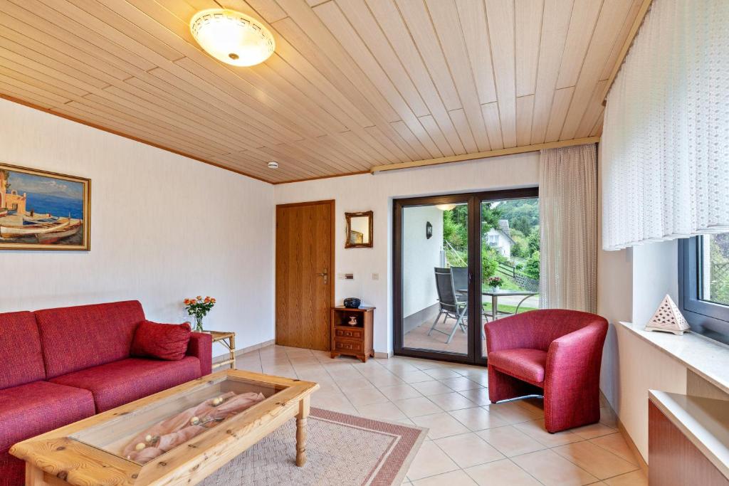a living room with a red couch and a table at Ferienwohnung Klug in Haintchen