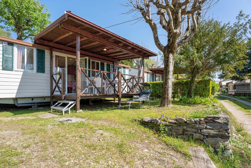 a house with a porch and a tree at Camping Royal in Pettenasco