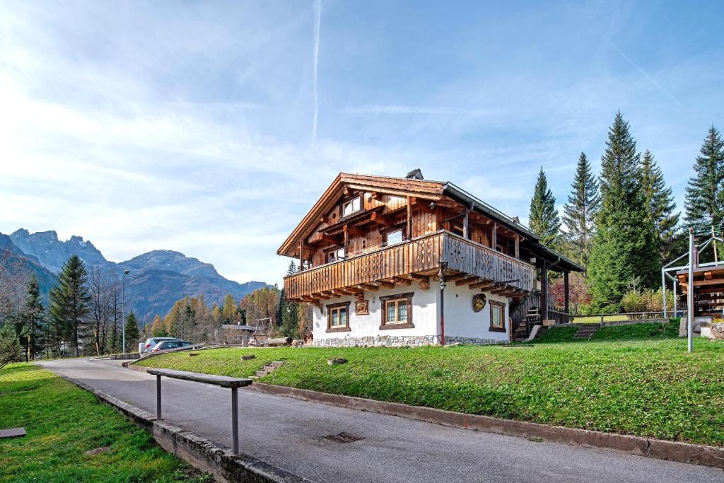 a house with a wooden roof on the side of a road at Appartamenti Marmolada Falcade in Falcade