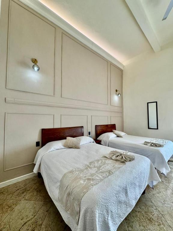 two beds in a room with white walls at Hotel Catedral in Cuernavaca