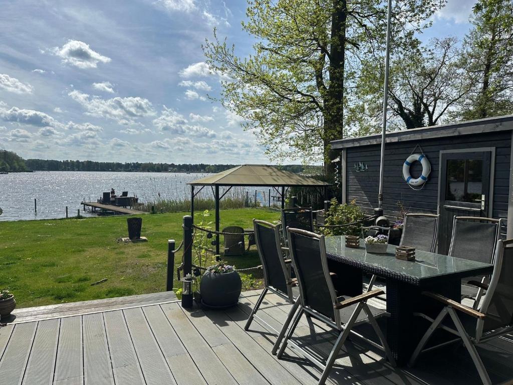 a deck with a table and chairs next to a lake at Häuser am See in Königs Wusterhausen