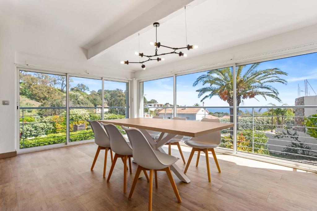 a dining room with a table and chairs and large windows at Villa Palmier avec piscine in Roquebrune-sur-Argens