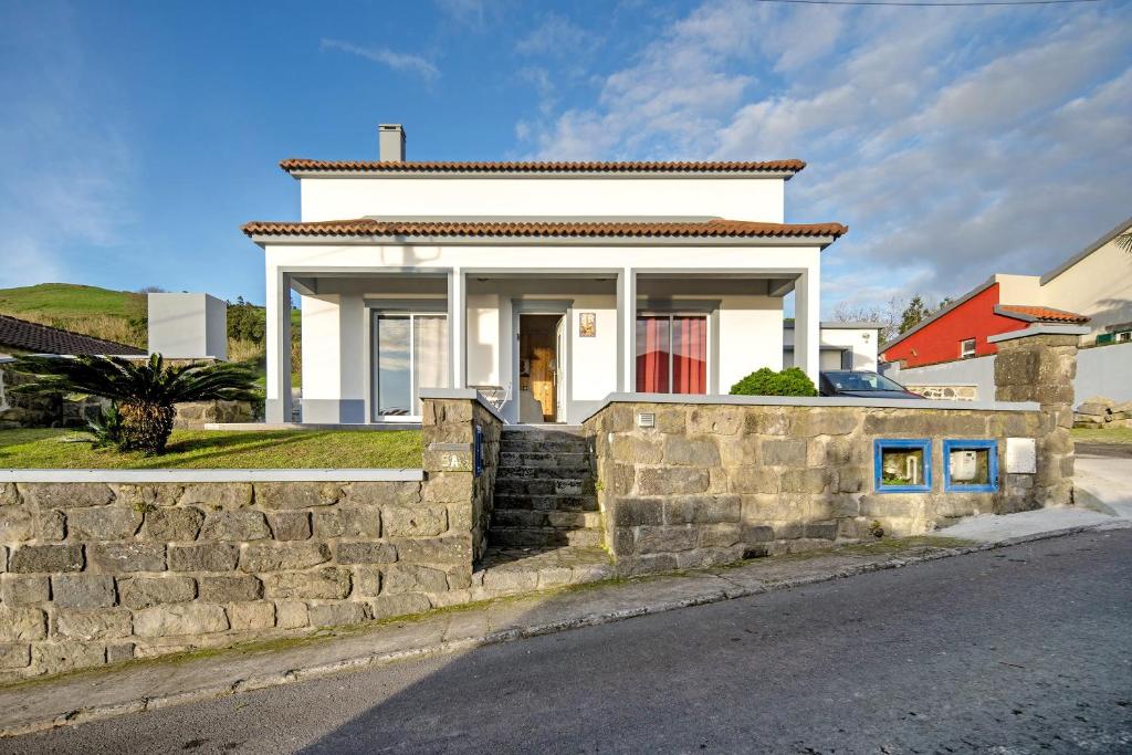 a white house behind a stone wall at Cantinho do Sossego in Várzea