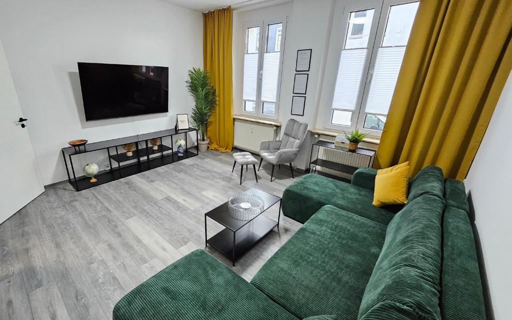 a living room with a green couch and a flat screen tv at Relax in der Röntgenstadt in Remscheid