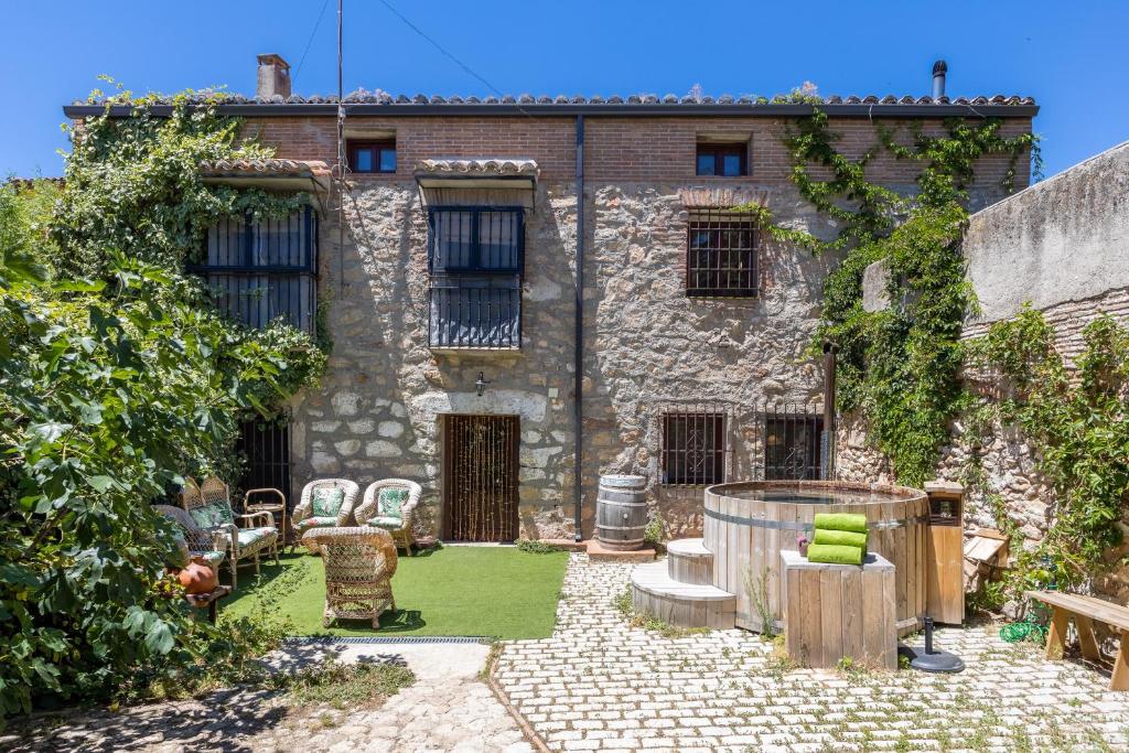 an old stone house with a garden in front of it at La Casona Del Tio Pedro in Cadalso de los Vidrios