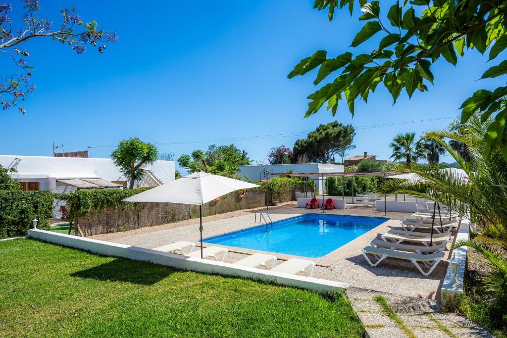 a swimming pool with chairs and an umbrella at Finca Blanca in Calas de Mallorca