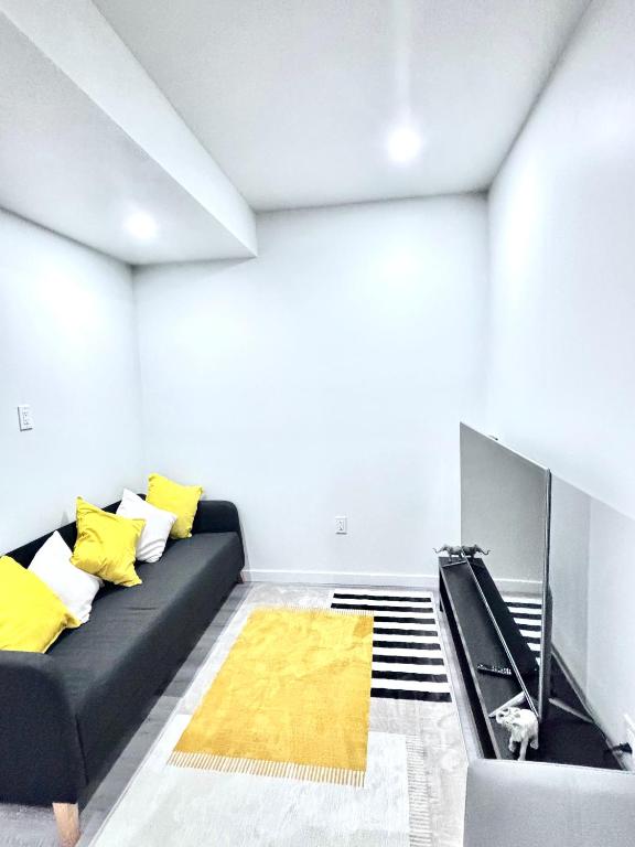 a living room with a black couch and yellow pillows at Cozy Home basement suite with private separate entrance in Winnipeg