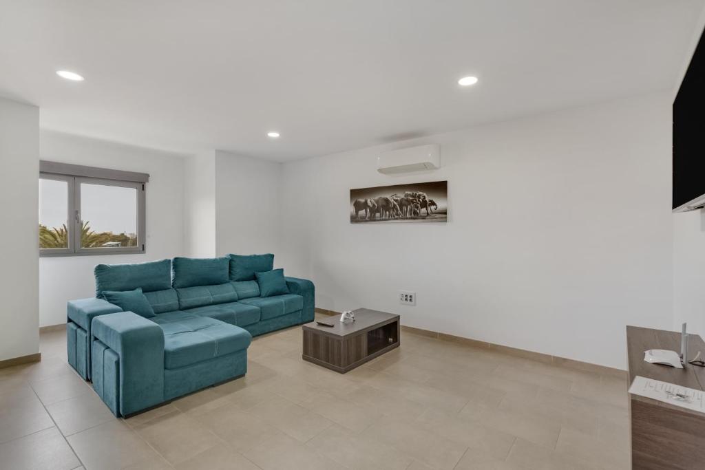 a living room with a blue couch and a table at Edificio Bentejui 2 in Las Palmas de Gran Canaria