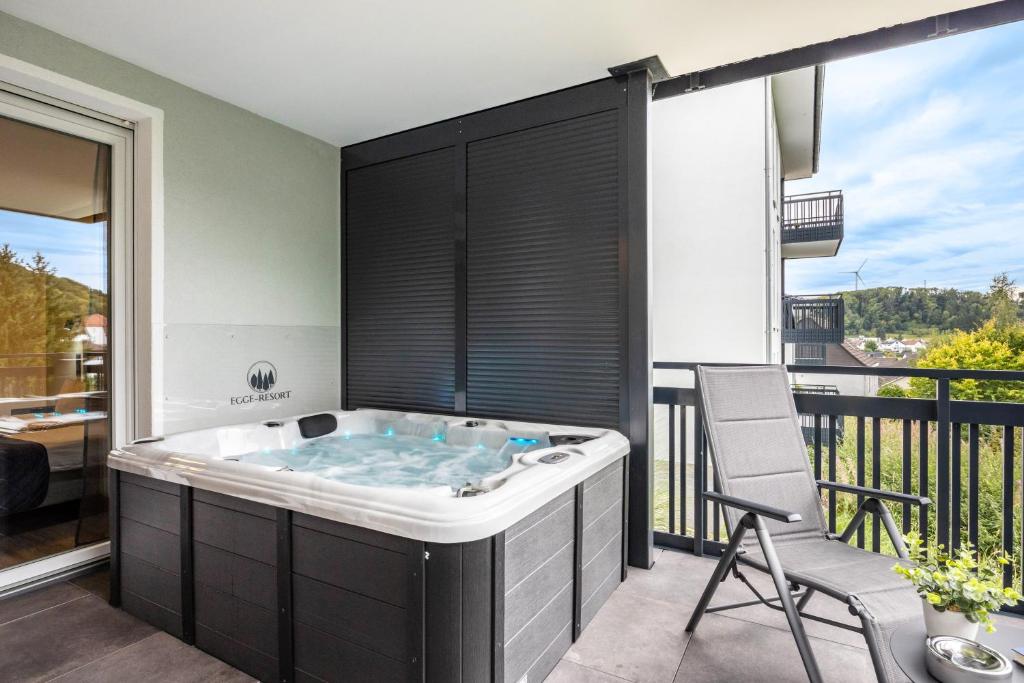 a jacuzzi tub in a balcony with a chair at Egge Resort 7g mit Whirpool u Sauna in Altenbeken
