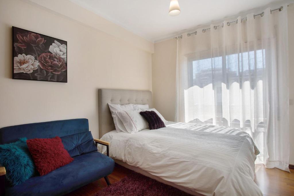 a bedroom with a bed and a blue couch at T0 Grota in Buarcos