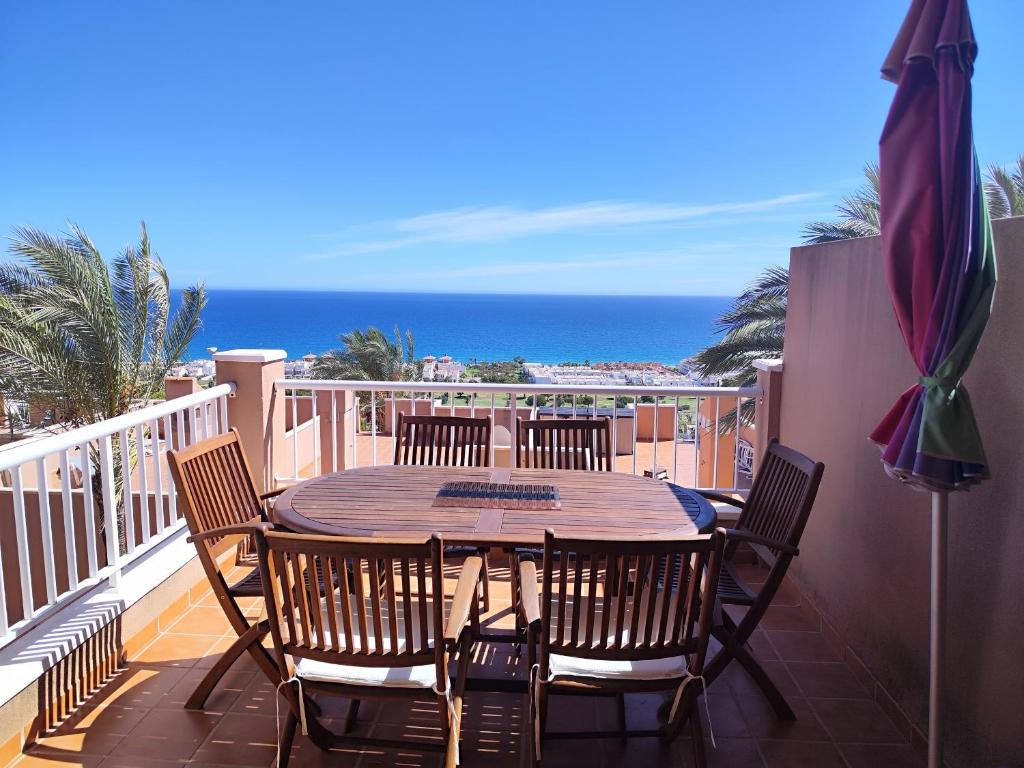 a wooden table and chairs on a balcony with the ocean at Marina Golf in Mojácar