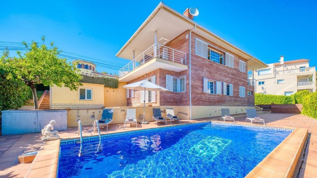 a house with a swimming pool in front of a house at Costacabana - Villa Beyonce in Lloret de Mar