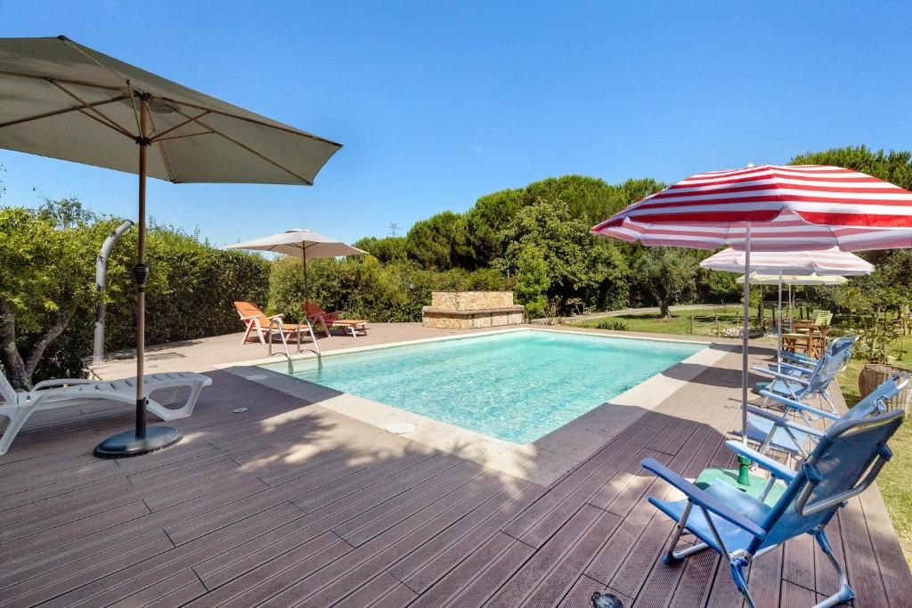 a swimming pool with two chairs and an umbrella at Quinta O Refúgio in Azambuja